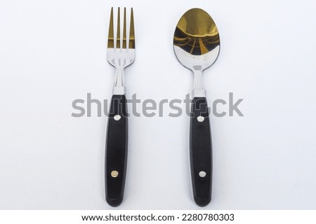 close up of spoon and fork made of stainless steel combination of black handles with white background