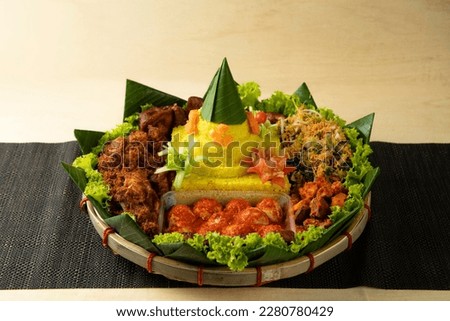 Nasi Tumpeng is a traditional ceremonial snack for the Javanese, Balinese, Madurese and Sundanese people in which the rice is served in a cone shape, yellow in color and arranged together with the sid Royalty-Free Stock Photo #2280780429