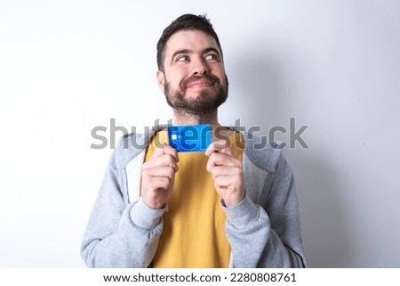 Photo of cheerful Young caucasian mán wearing trendy clothes over white background hold debit card look empty space