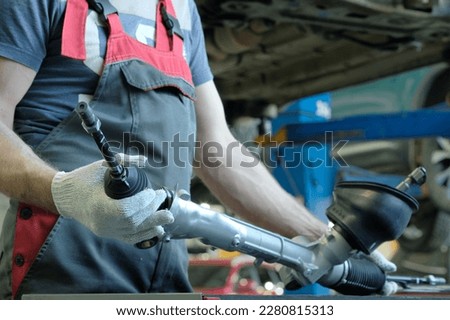 Spare parts for the car. Steering rack.  A component of the hydraulic power steering. An auto mechanic monitors the technical condition of a new spare part. Royalty-Free Stock Photo #2280815313