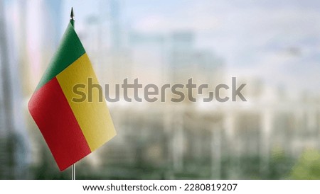 Small flags of the Benin on an abstract blurry background.