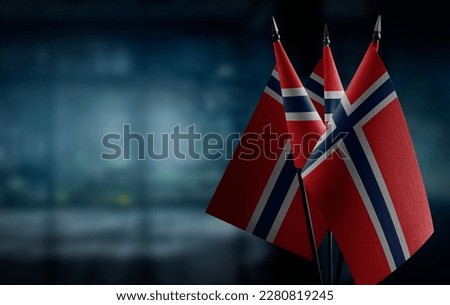 Small flags of the Norway on an abstract blurry background.
