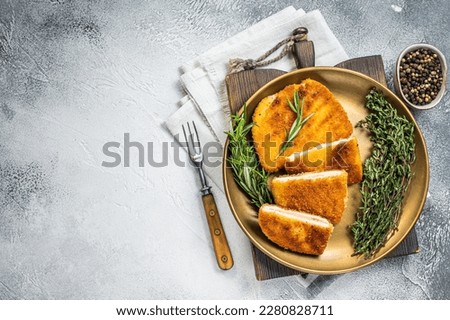 Chicken fried Cordon bleu cutlet with ham and cheese on a plate with herbs. White background. Top view. Copy space. Royalty-Free Stock Photo #2280828711