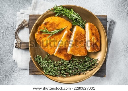 Chicken fried Cordon bleu cutlet with ham and cheese on a plate with herbs. White background. Top view. Royalty-Free Stock Photo #2280829031