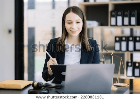 Justice and law concept. Female judge in a courtroom with the gavel working with digital tablet computer docking keyboard on wood table.