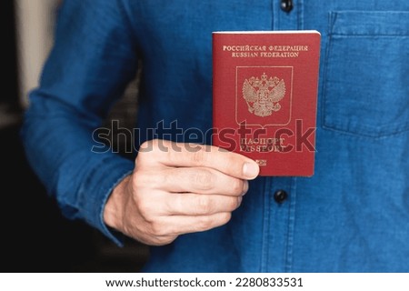 Russian foreign passport in the right hand of a man in a blue denim shirt Royalty-Free Stock Photo #2280833531