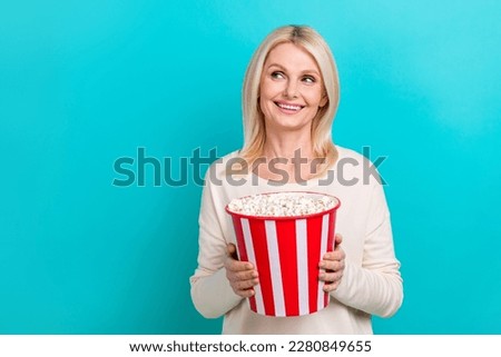 Photo of attractive lady wear shirt hold basket pop corn eating snacks looking empty space new film advertisement isolated on blue color background