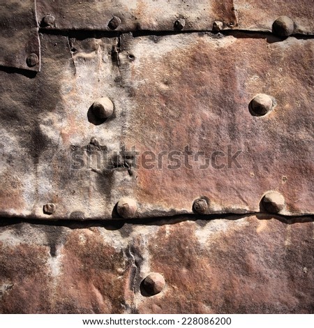 Vintage rusty iron background - metal plates with bolts. Grunge texture. Square composition.