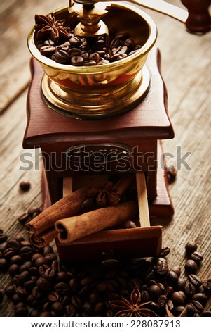 Coffee grinder, coffee beans, cinnamon and anise on wooden background