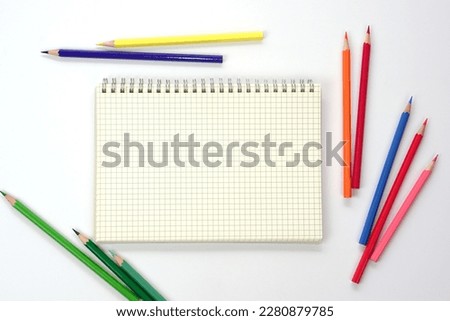 Graph book with colored pencils or pastel lined up on white background. Learning, study and presentation concept.