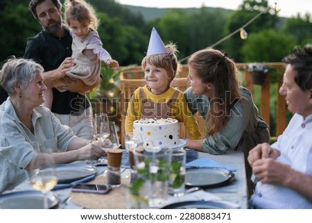 Multi generation family celebrating birthday and have garden party outside in the backyard on patio. Royalty-Free Stock Photo #2280883471