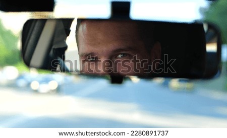 Close up of young cheerful man inside the car. Handsome Caucasian male driving his car and smiles while looking at rear view mirror. Blurred background. Happy driver in automobile, trip concept Royalty-Free Stock Photo #2280891737
