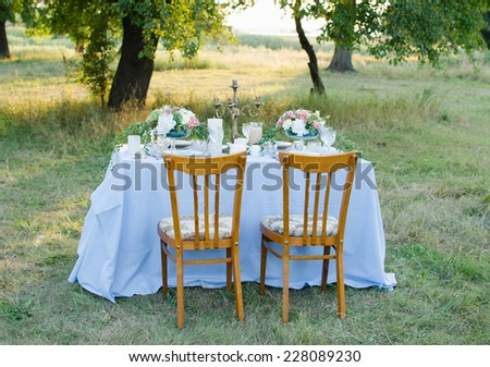 beautifully laid a festive table for two in the garden with flowers and candles