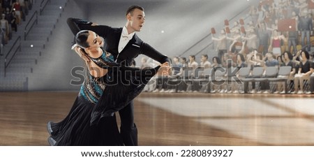 Graceful dancer. Young artistic man and woman in beautiful stage costumes dancing ballroom dance at stage under spotlights. Competition. 3D audience background. Concept of art, movements, beauty Royalty-Free Stock Photo #2280893927