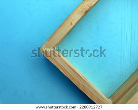 Empty wooden picture frame square box isolated in colorful gradient blue background. Selective focus