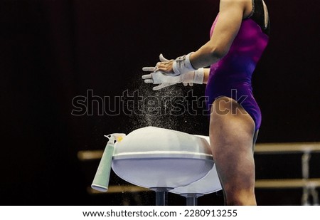 female gymnast puts magnesia on her hands before performing on uneven bars gymnastics, sports summer games 