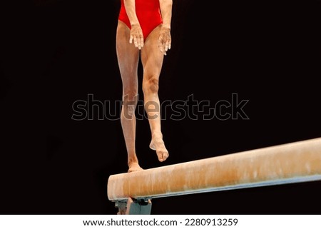 legs female gymnast in red swimsuit exercise balance beam gymnastics on dark background, sports summer games 