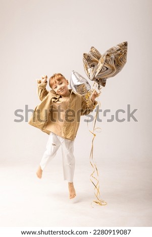 People, joy, fun and happiness concept. Relaxed happy birthday little boy looking cheerful, smiling happily, posing for picture, holding colorful helium balloons