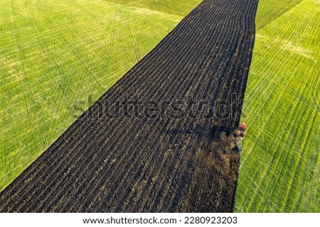 the field of the agricultural holding on which the tractor is working, view from the drone. red tractor on green field aerial photo