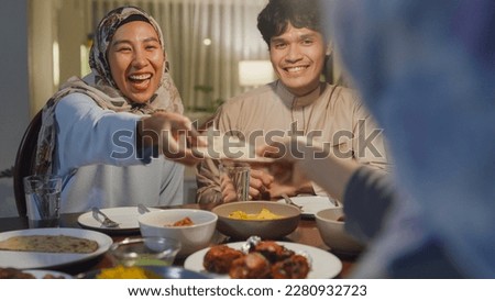 Eid Mubarak Muslim Asia family have Iftar dinner sister share bread to sibling for break fasting. Traditional food during Ramadan month at home, The Islamic Halal Eat and Drink at modern Islam. Royalty-Free Stock Photo #2280932723