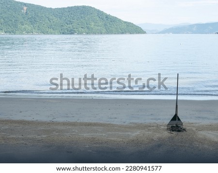 Sand sweeping brush to sweep the sand standing up. Calm sea in t