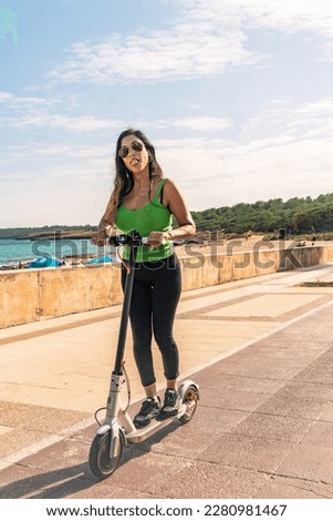Woman riding electric scooter, happy and summer ride at tropical island beach resort for vacation. City, street and eco friendly transport, fun on escooter on holiday in mallorca,balearic island Royalty-Free Stock Photo #2280981467
