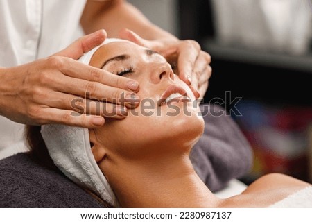 Shot of a beautiful young woman enjoying face massage at the beauty salon. Royalty-Free Stock Photo #2280987137