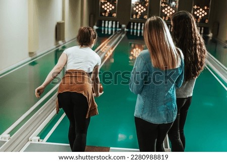 Three female friends having fun while bowling and speding time together.