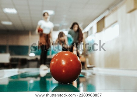 Close-up of a three female friends having fun while bowling. Selective focus, focus on the bowling ball at lane.