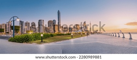 breathtaking view of Abu Dhabi's embankment skyline as the sun sets in the horizon, casting a warm orange glow on the towering skyscrapers