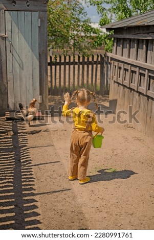 Funny playful girl has fed the chickens and waves goodbye to her friends. Breeding poultry on the farm