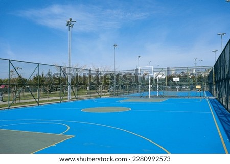 Basketball court in park. Outdoor public basketball field with nobody, blue surface, summer, sunny day