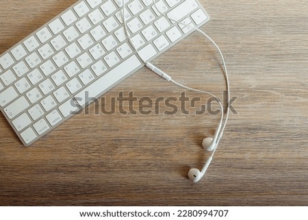 Headphones with a keyboard lie on a wooden table