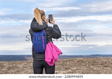 Sporty young blonde woman photographing landscape with mobile phone