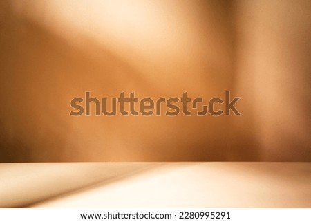 Mock up for presentation, branding products, cosmetics, food or jewellery. Empty table on bright brown wall background. Composition with leaves shadow on the wall and wooden desk. 