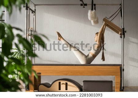 Pilates fitness trainer doing exercises on in pilates studio. Balanced Body Cadillac machine for fitness workouts in gym. Fit, healthy and strong authentical body. Fitness concept. Royalty-Free Stock Photo #2281003393