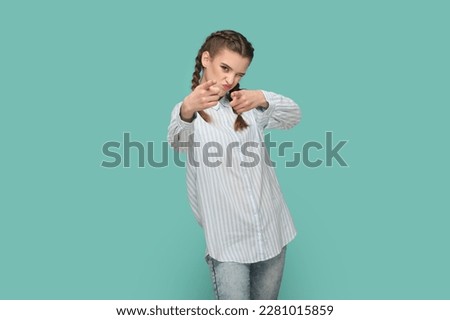 Portrait of positive optimistic flirting teenager girl with braids wearing striped shirt pointing fingers to camera, choosing you. Indoor studio shot isolated on green background.