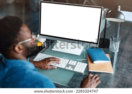 Unrecognizable black businessman using computer with empty blank screen, sitting at workplace in office, offering space for mockup on monitor. Male CEO showing place for online ad Royalty-Free Stock Photo #2281024747