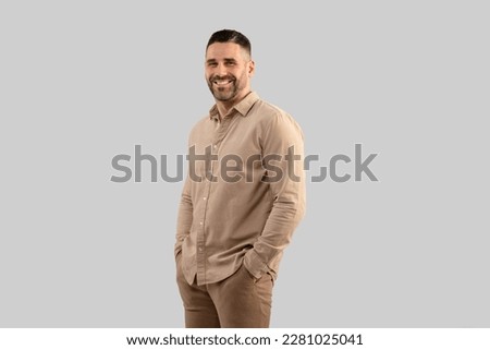 Portrait of positive middle aged man in shirt posing with hands in pockets over light grey studio background, looking at camera and smiling, copy space Royalty-Free Stock Photo #2281025041