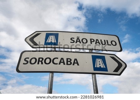 Sorocaba, Sao Paulo. Traffic sign signaling the direction to the cities of Sorocaba on the right and São Paulo on the left. Blue sky with white clouds in the background.