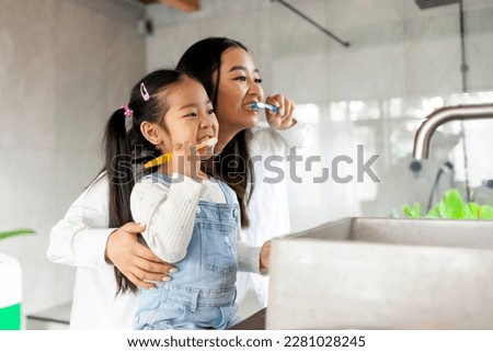 asian little girl with mom brushing teeth in bathroom, korean woman helping to brush daughter's teeth at home together, asian family and hygiene procedures Royalty-Free Stock Photo #2281028245