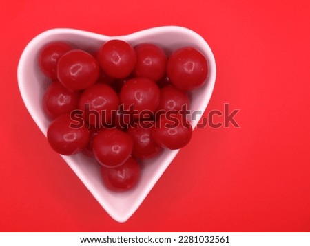 cherry flavored candies in a heart shaped ceramic bowl. on a contrasting background, celebrating valentine's day