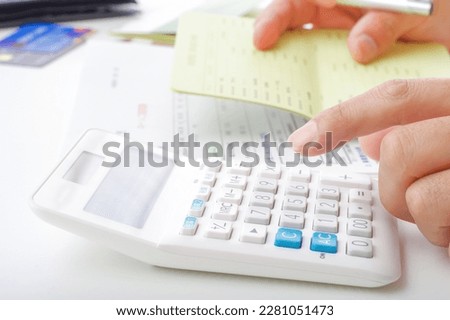 The hand of a man who calculates money with a calculator.

The blue button of the calculator says "tax rate" in Japanese. Royalty-Free Stock Photo #2281051473