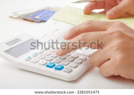 The hand of a man who calculates money with a calculator.

The blue button of the calculator says "tax rate" in Japanese. Royalty-Free Stock Photo #2281051475