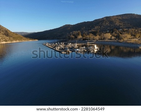 a majestic aerial shot of the vast blue still lake water with breathtaking mountain ranges reflecting off the lake at sunset with colorful boats on the dock at Silverwood Lake in Hemet California USA	