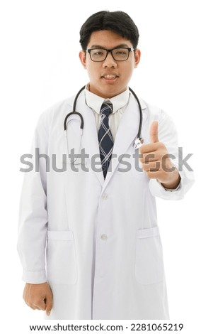 Isolated cutout studio shot of Asian young professional male doctor in lab coat with stethoscope and eyeglasses standing holding scrolling touchscreen tablet reading patient data on white background.