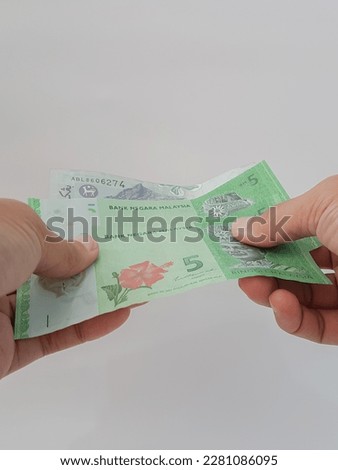 person's hand holding several Malaysia ringgit banknotes on White isolated background 