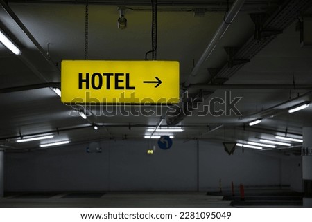 Yellow glowing Hotel information sign in an underground car park with white neon lighting