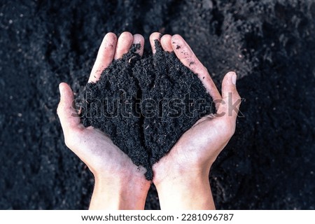 Hands holding abundance soil for agriculture or preparing to plant  Testing soil samples on hands with soil ground background. Dirt quality and farming concept. Selective focus on black soil in front Royalty-Free Stock Photo #2281096787