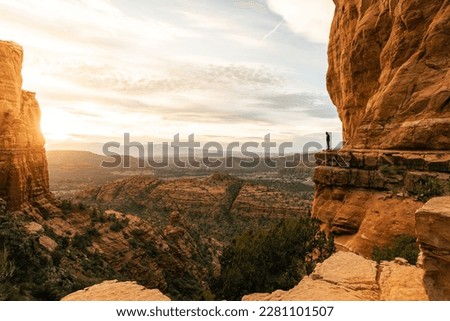 Woman looking down at cliff during dramatic sunset from Cathedral Rock. Royalty-Free Stock Photo #2281101507